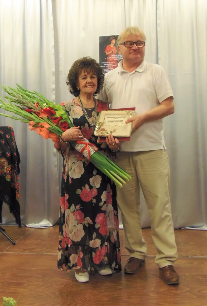 Na scenie stoi Pani Hanna Michalik oraz Dyrektor Centrum Alzheimera Pan Jarosław Gnioska, który wręcza kwiaty artystce